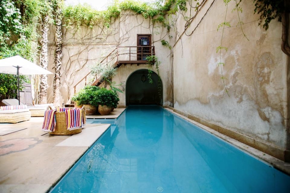 Long pool in a walled courtyard with an arched opening at the end