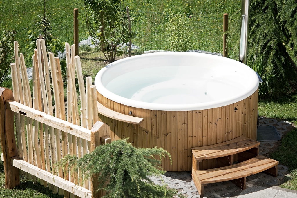 Timber-clad hot tub on a garden terrace with a step and screen