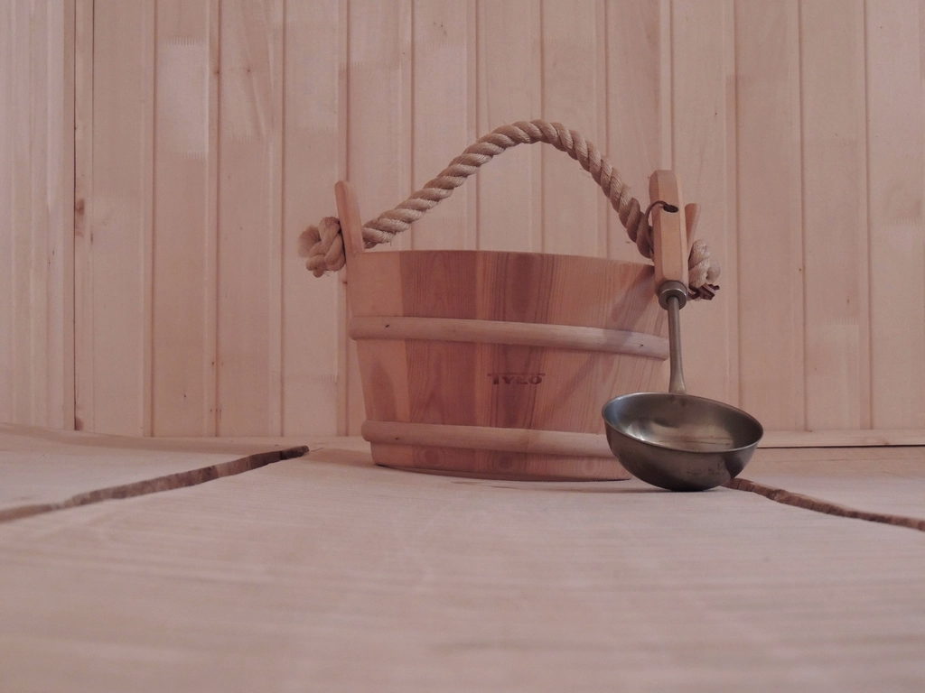 Sauna bucket and ladle on a pale timber bench