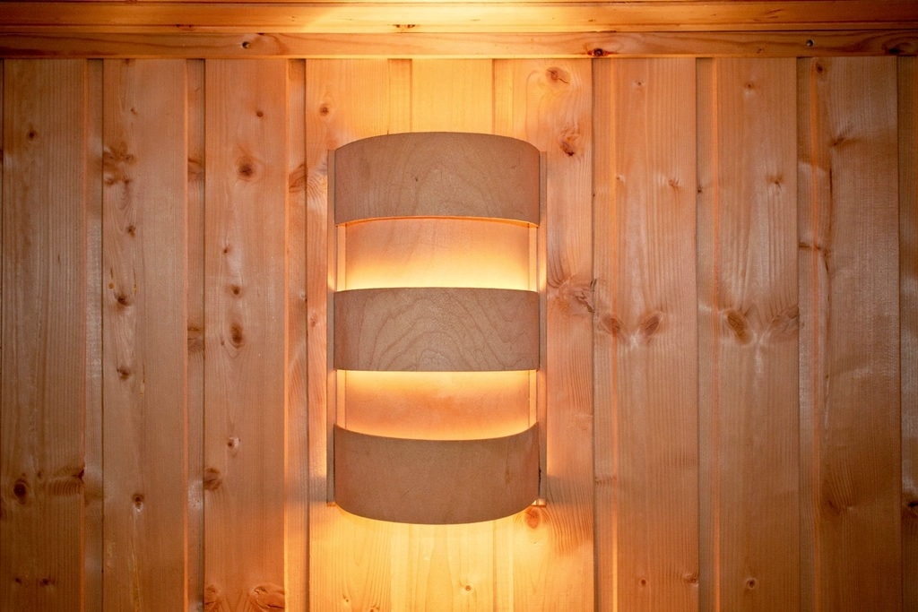 Shielded sauna wall light against tongue-and-groove timber