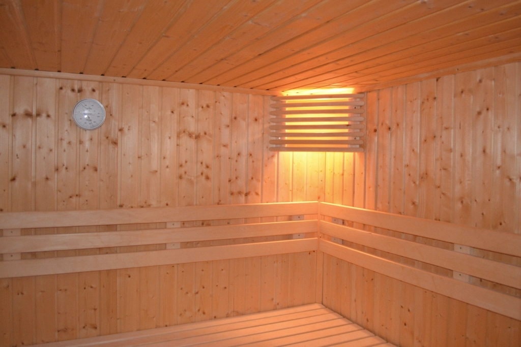Corner of a pale sauna with a backlit ceiling vent